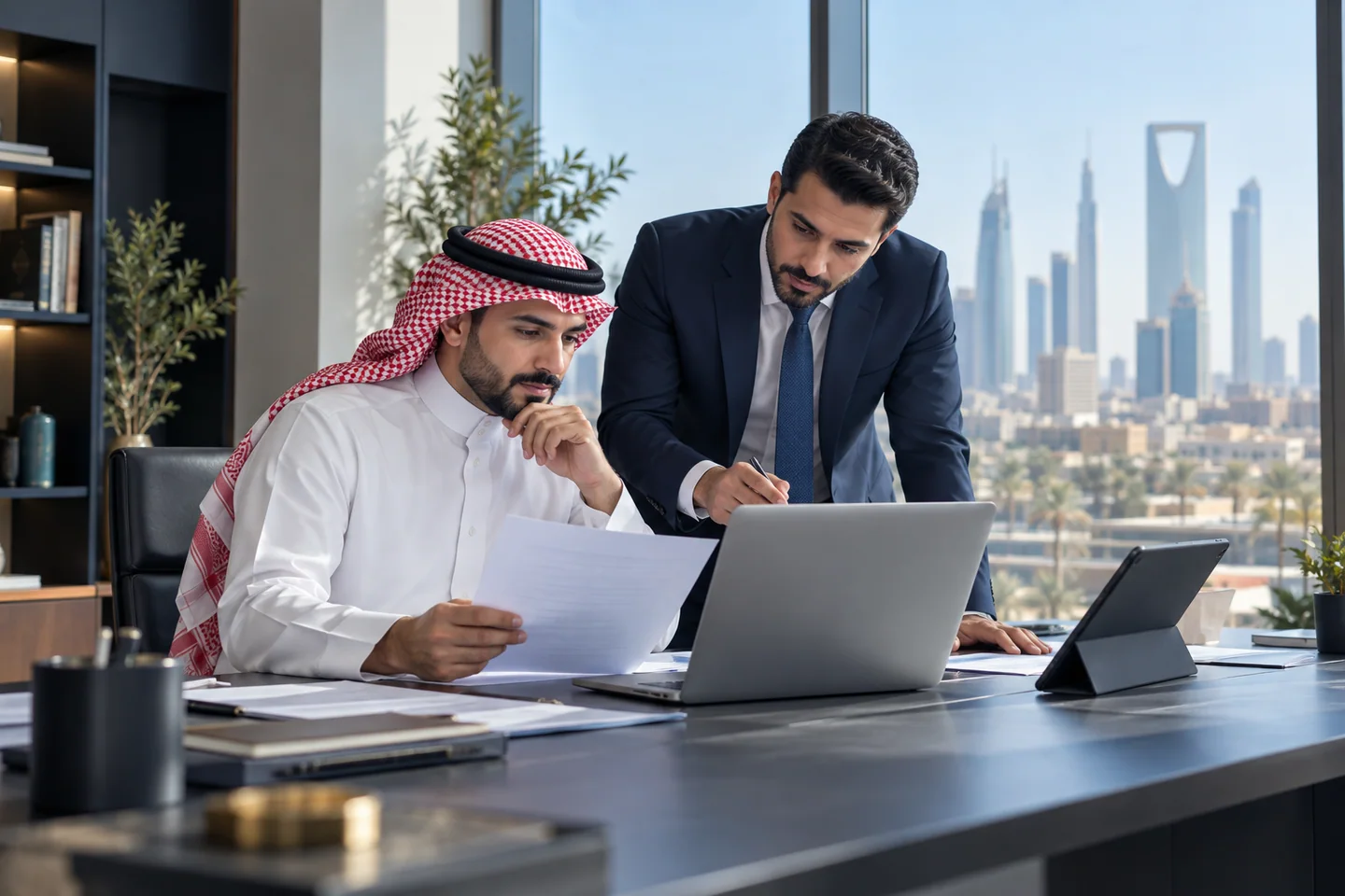صاحب أعمال سعودي يراجع الحسابات مع زميل في مكتب
